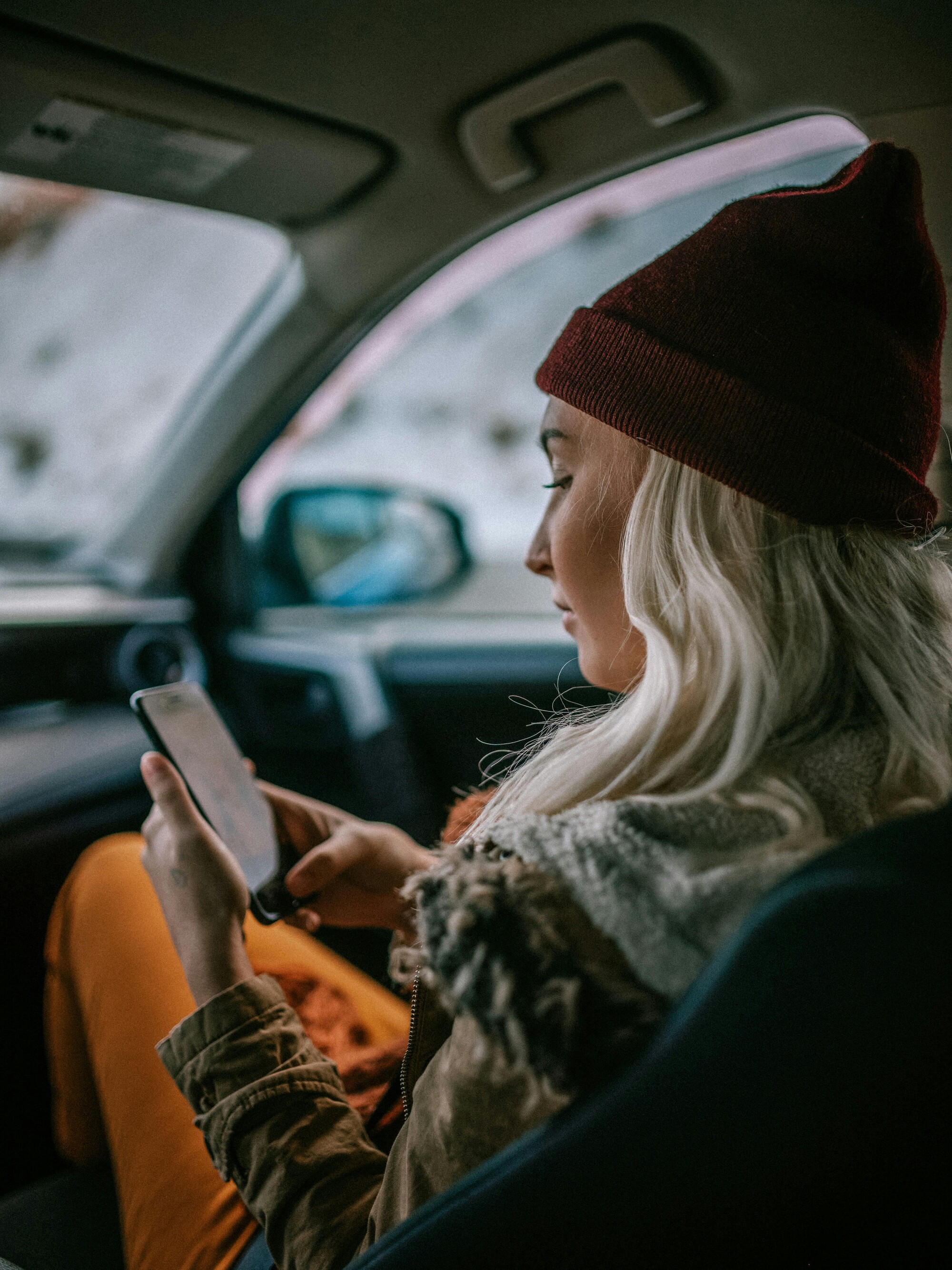 Mulher ouvindo a Biblia no celular dentro do carro com expressao tranquila